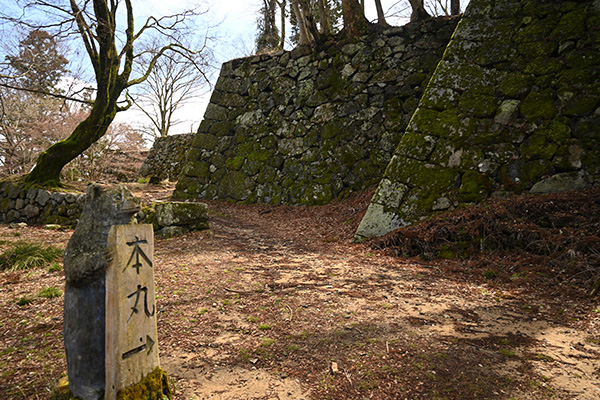 「本丸」の案内札を持つ熊の像と高取城本丸の石垣